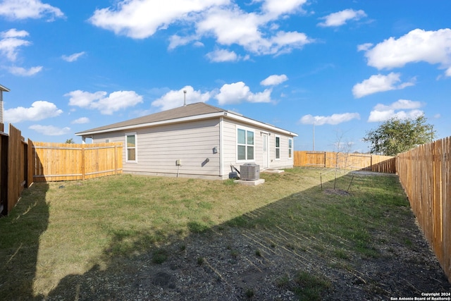 back of property with central AC unit and a lawn