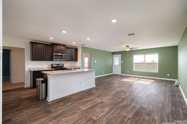 kitchen featuring dark brown cabinetry, ceiling fan, dark wood-type flooring, an island with sink, and appliances with stainless steel finishes