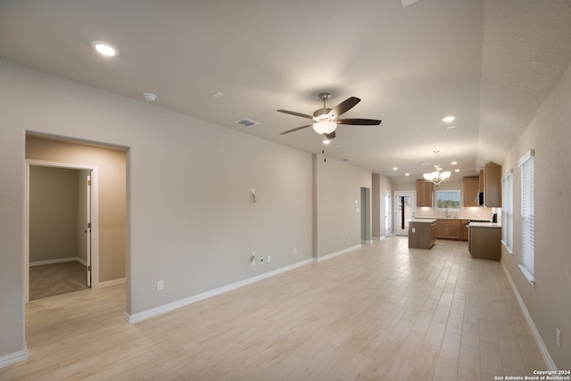 unfurnished living room with ceiling fan with notable chandelier and light hardwood / wood-style floors