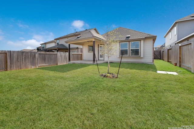 rear view of property with a yard, ceiling fan, and a patio area