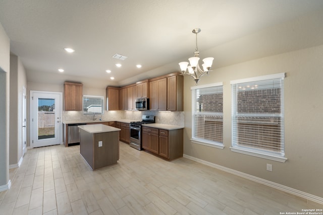 kitchen featuring stainless steel appliances, light hardwood / wood-style flooring, a notable chandelier, a center island, and hanging light fixtures