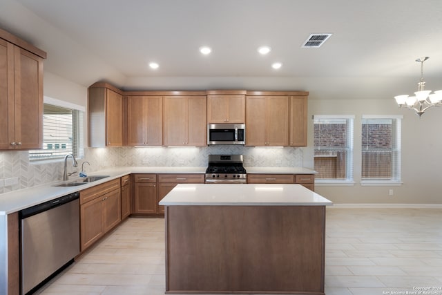 kitchen with pendant lighting, sink, decorative backsplash, appliances with stainless steel finishes, and a notable chandelier