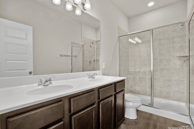 bathroom with an enclosed shower, vanity, toilet, and wood-type flooring