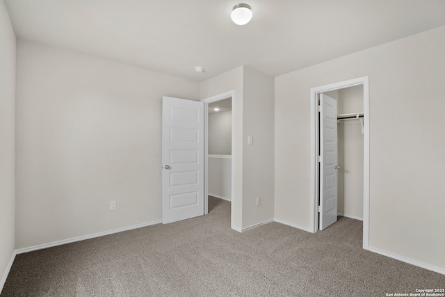 unfurnished bedroom featuring carpet, a walk in closet, and a closet