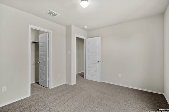 unfurnished bedroom with carpet, a walk in closet, and a closet