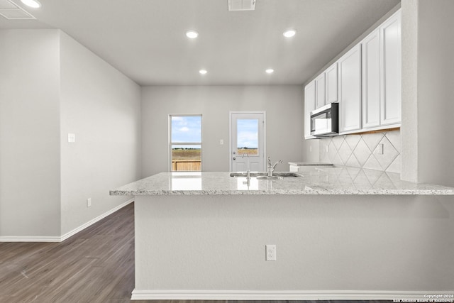 2087 Olivia Dr, New Braunfels, TX 78130 - kitchen with a peninsula, a sink, stainless steel microwave, recessed lighting, and light stone counters