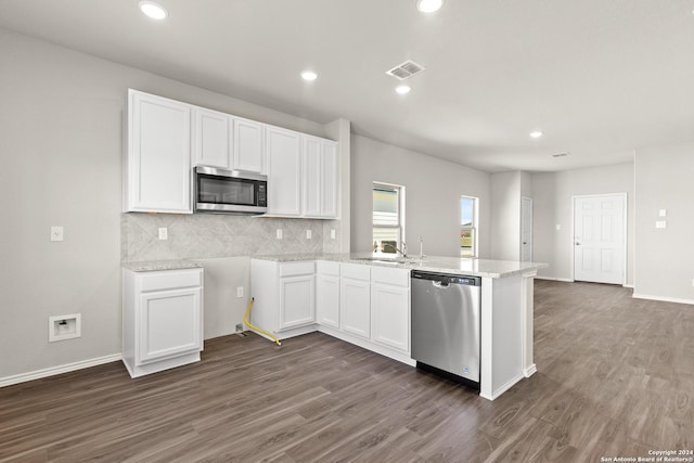 2087 Olivia Dr, New Braunfels, TX 78130 - kitchen with appliances with stainless steel finishes, white cabinetry, a peninsula, tasteful backsplash, and dark wood finished floors