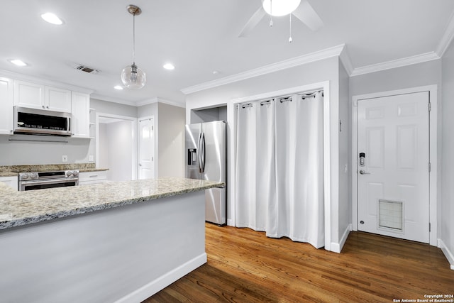 kitchen featuring pendant lighting, dark wood-type flooring, white cabinets, crown molding, and appliances with stainless steel finishes