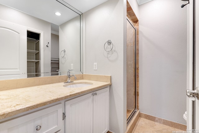 bathroom with toilet, vanity, tile patterned floors, and a shower with door