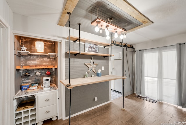 interior space featuring white refrigerator, white cabinetry, a barn door, and dark wood-type flooring