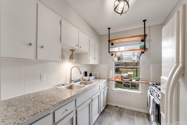 kitchen featuring white cabinetry, sink, stainless steel stove, and white refrigerator with ice dispenser