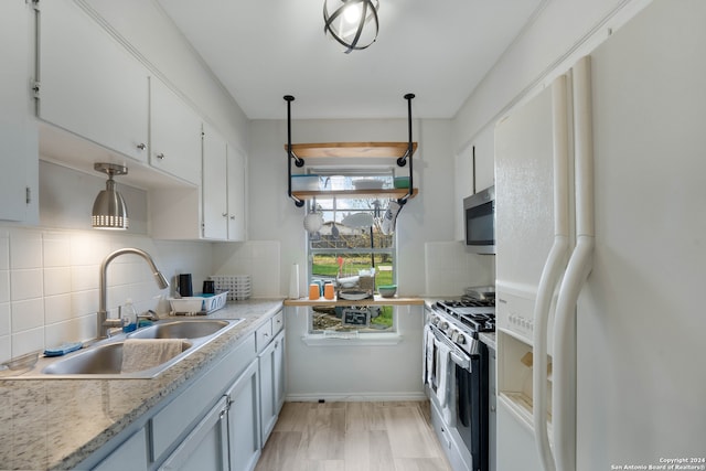 kitchen featuring white cabinetry, sink, decorative light fixtures, appliances with stainless steel finishes, and light wood-type flooring