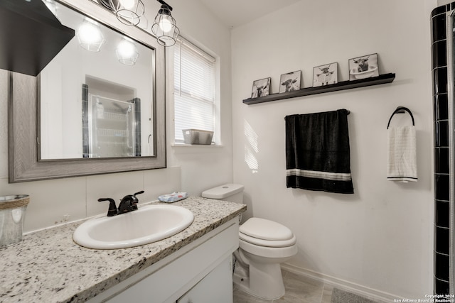 bathroom with tile patterned flooring, vanity, a shower with shower door, and toilet