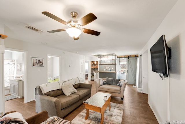 living room featuring light wood-type flooring, a barn door, and ceiling fan