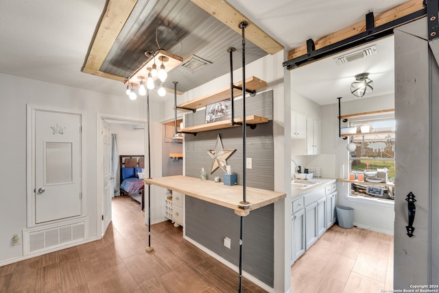 kitchen with white cabinets, light wood-type flooring, decorative light fixtures, and sink