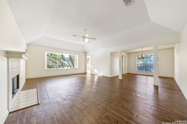 unfurnished living room with dark hardwood / wood-style flooring, plenty of natural light, ceiling fan with notable chandelier, and a tiled fireplace