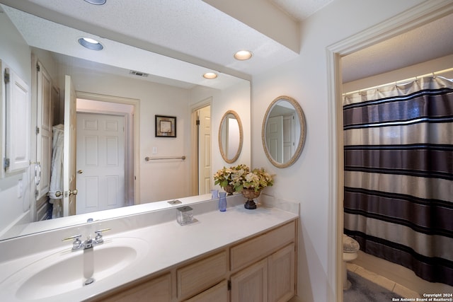 bathroom with vanity, toilet, and a textured ceiling