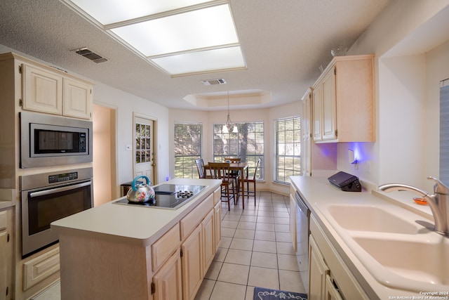 kitchen with sink, stainless steel appliances, a textured ceiling, decorative light fixtures, and a kitchen island