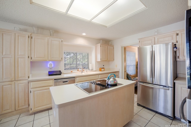 kitchen with appliances with stainless steel finishes, light tile patterned floors, a kitchen island, and sink