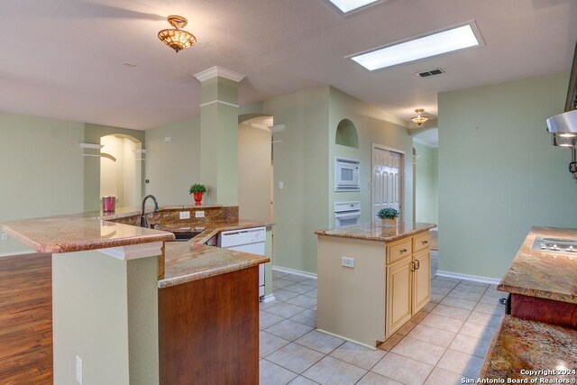 kitchen with sink, white appliances, light stone countertops, and a center island