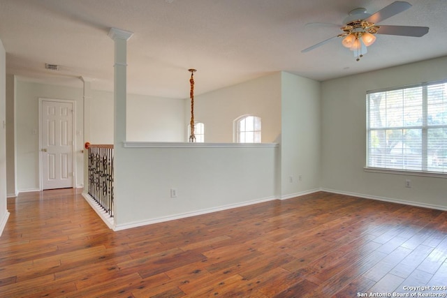 unfurnished room featuring a healthy amount of sunlight, dark wood-type flooring, and ceiling fan