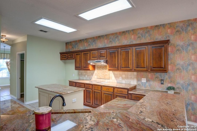 kitchen with white cooktop, light stone countertops, and a kitchen island