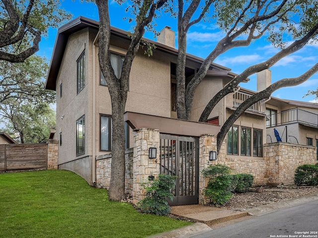 view of front of house with a balcony and a front yard