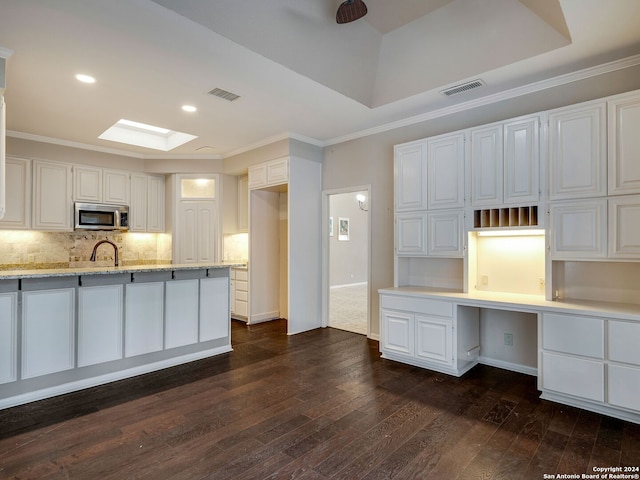 kitchen with white cabinets, decorative backsplash, dark hardwood / wood-style flooring, and a skylight