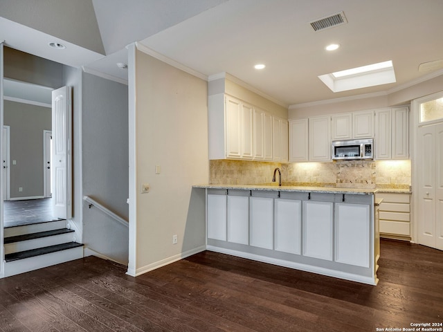 kitchen with light stone counters, dark hardwood / wood-style flooring, white cabinetry, and kitchen peninsula