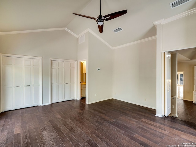 unfurnished bedroom with ornamental molding, two closets, ceiling fan, dark wood-type flooring, and high vaulted ceiling