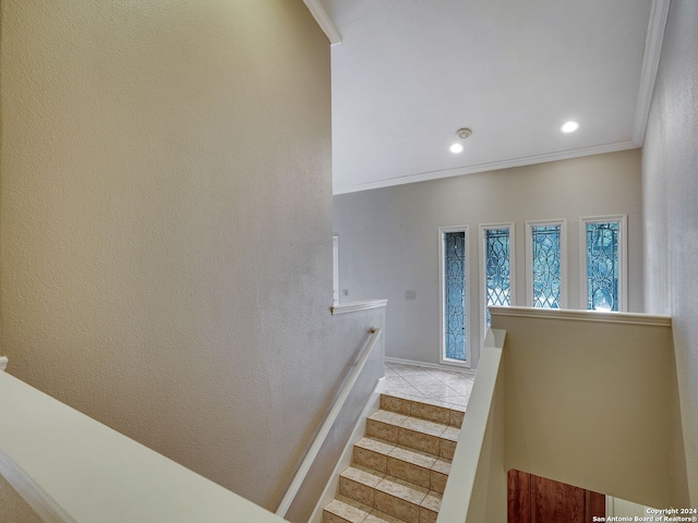 stairway with tile patterned floors and crown molding