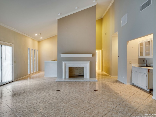 unfurnished living room with sink, a high ceiling, a fireplace, light tile patterned floors, and ornamental molding