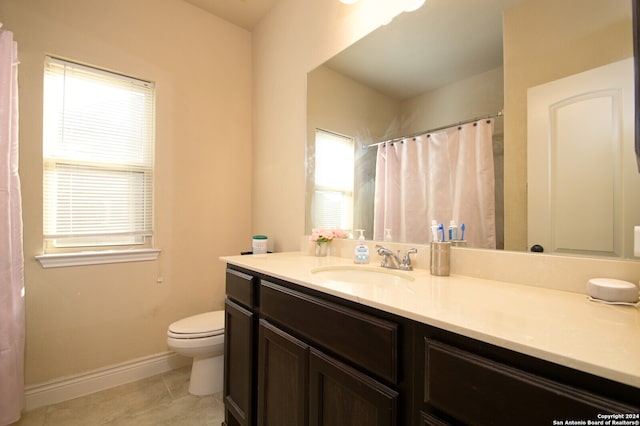 bathroom with tile patterned floors, vanity, a healthy amount of sunlight, and toilet