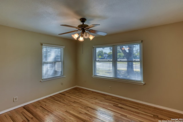 empty room with ceiling fan, light hardwood / wood-style floors, and a textured ceiling