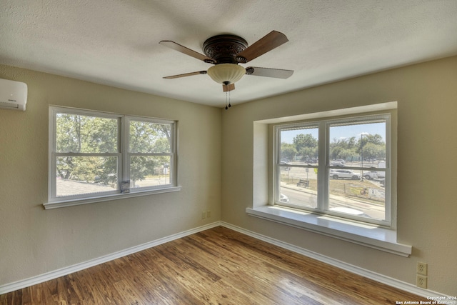 empty room with a wall unit AC, ceiling fan, light hardwood / wood-style flooring, and a healthy amount of sunlight