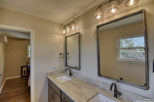 bathroom with hardwood / wood-style floors, vanity, a textured ceiling, and a wall unit AC