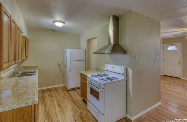 kitchen with a textured ceiling, white appliances, wall chimney range hood, and sink