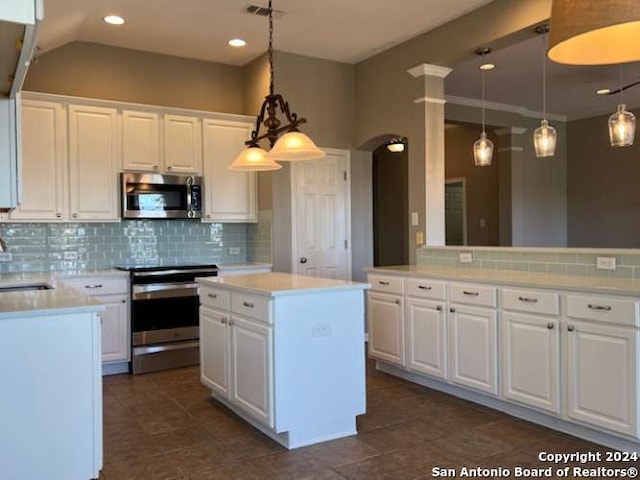 kitchen featuring white cabinetry, hanging light fixtures, backsplash, a kitchen island, and appliances with stainless steel finishes