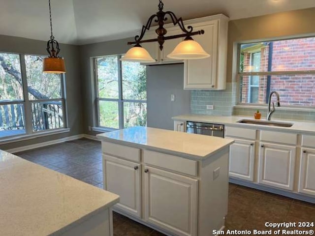 kitchen featuring a kitchen island, sink, pendant lighting, dishwasher, and white cabinetry