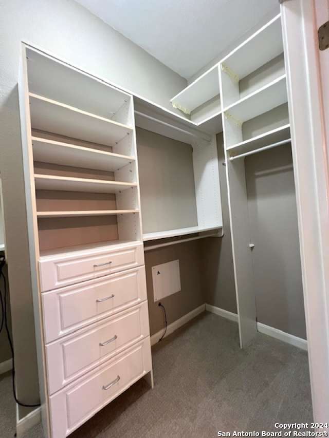 spacious closet featuring dark colored carpet and built in desk