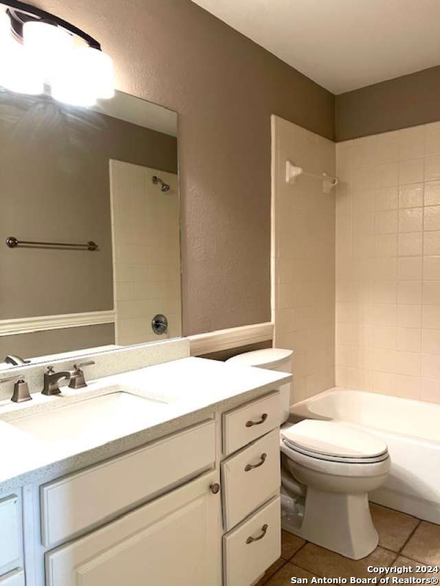 full bathroom featuring tile patterned floors, vanity, tiled shower / bath combo, and toilet