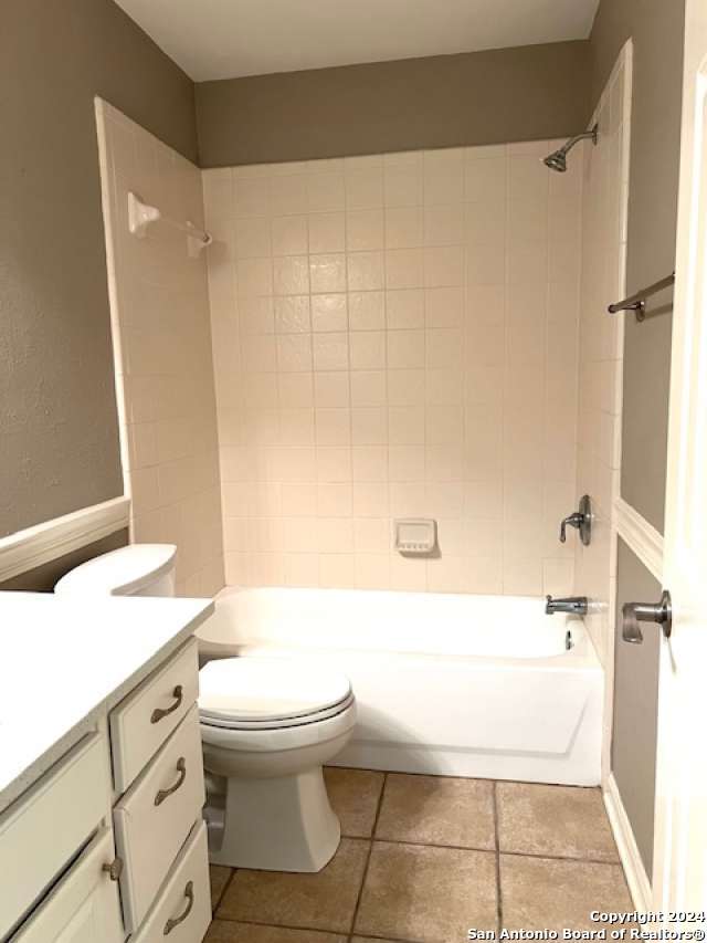 full bathroom featuring tile patterned floors, vanity, tiled shower / bath combo, and toilet