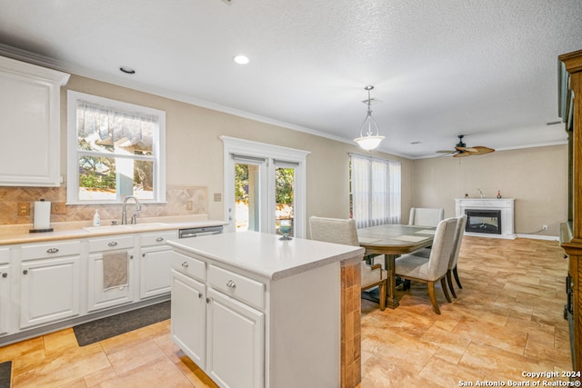 kitchen featuring pendant lighting, backsplash, white cabinetry, and sink