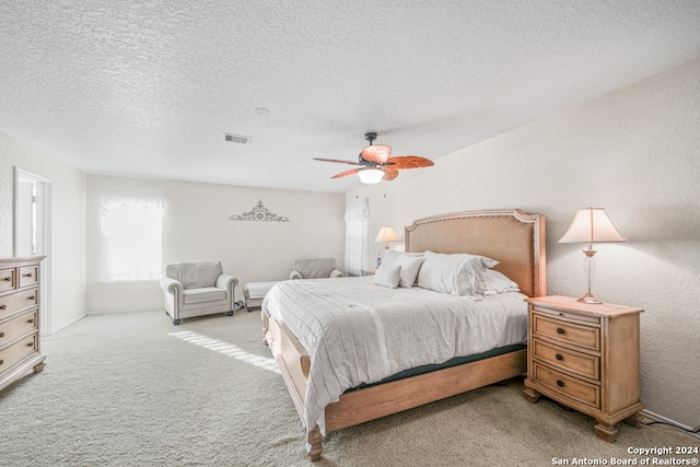 bedroom featuring ceiling fan, light colored carpet, and a textured ceiling