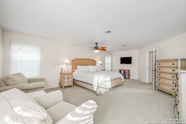 bedroom featuring ceiling fan, light carpet, and a textured ceiling