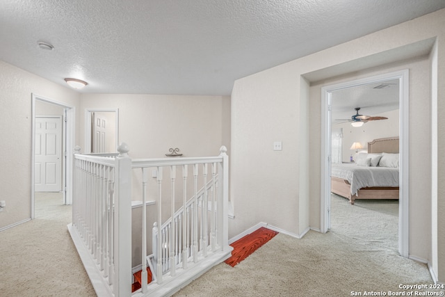 hallway featuring a textured ceiling and light colored carpet