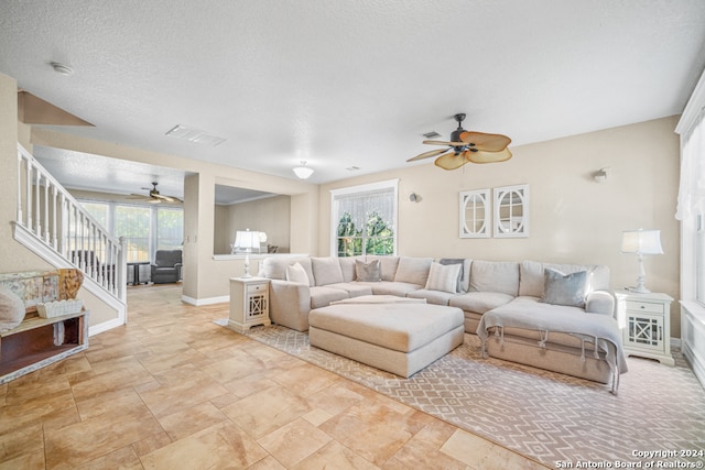 living room with a textured ceiling, plenty of natural light, and ceiling fan