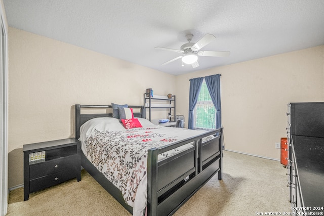 bedroom with a textured ceiling, ceiling fan, and light carpet