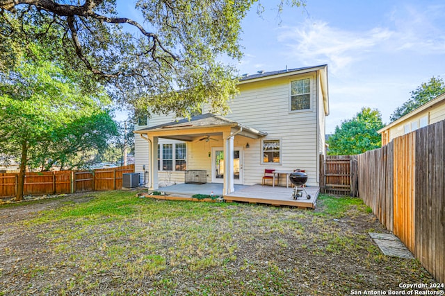 back of house featuring central air condition unit, a wooden deck, ceiling fan, and a yard