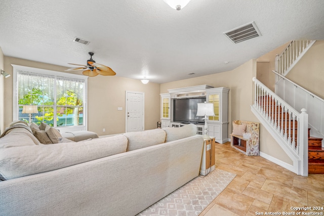 living room featuring ceiling fan and a textured ceiling